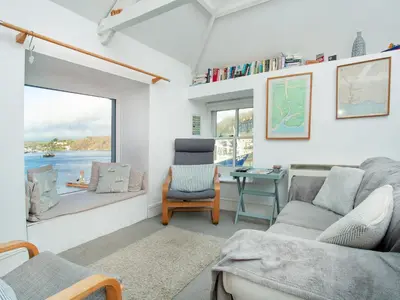 a living room with a couch and a chair and a window at The Lookout in Polruan