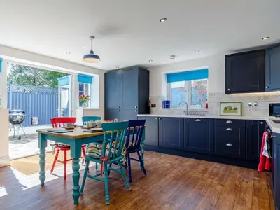 a kitchen with blue cabinets and a table and chairs at 2 Bed in Holsworthy oc-82455 in Week Saint Mary