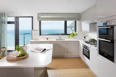 a kitchen with white cabinets and a table with a bowl of fruit at Scots Craig in St Ives