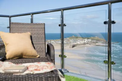 a chair on a balcony with a view of a beach at Scots Craig in St Ives