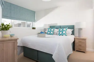 a bedroom with a large white bed with blue accents at Scots Craig in St Ives