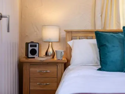 a bed with a nightstand with a clock and a lamp at 1 Bed in Helston oc-41377 in Cury
