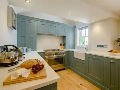 a kitchen with blue cabinets and a bowl of fruit on a cutting board at 3 Bed in Truro oc-87260 in Portloe