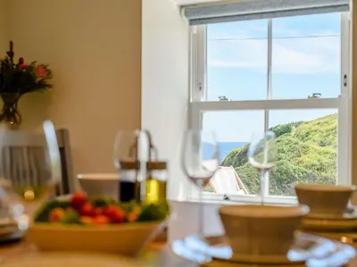 a table with a bowl of fruit in front of a window at 3 Bed in Truro oc-87260 in Portloe