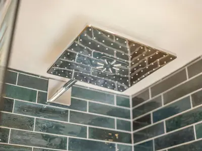 a shower head in a bathroom with green tiles at 3 Bed in Truro oc-87260 in Portloe