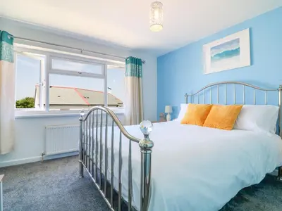 a blue bedroom with a bed and a window at Cres in Tintagel