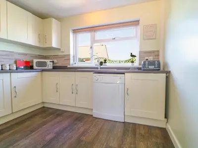 a kitchen with white cabinets and a window at Cres in Tintagel