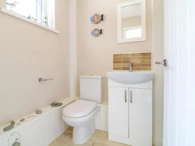 a white bathroom with a toilet and a sink at Cres in Tintagel