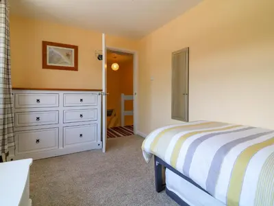 a bedroom with a bed and a dresser at Cres in Tintagel