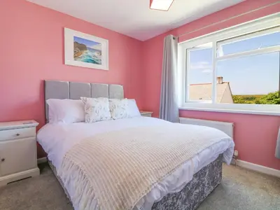 a bedroom with pink walls and a bed with a window at Cres in Tintagel