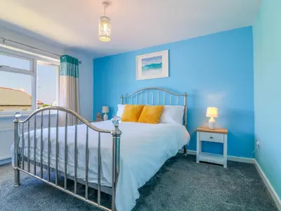a blue bedroom with a bed and a window at Cres in Tintagel