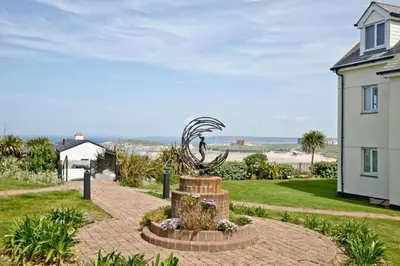 a statue in the middle of a brick walkway next to a house at Fistral beachside escape - dramatic ocean views in Crantock