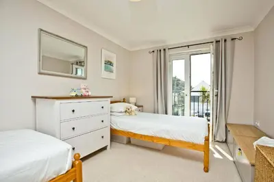 a bedroom with two beds and a mirror and a window at Fistral beachside escape - dramatic ocean views in Crantock