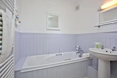 a white bathroom with a tub and a sink at Fistral beachside escape - dramatic ocean views in Crantock