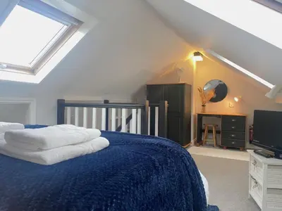 a bedroom with a blue bed and a television at 1 Bed in Nr Bude oc-penke in Saint Gennys