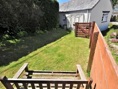two wooden benches sitting on a fence next to a house at 1 Bed in Bude oc-tchawth in Saint Gennys