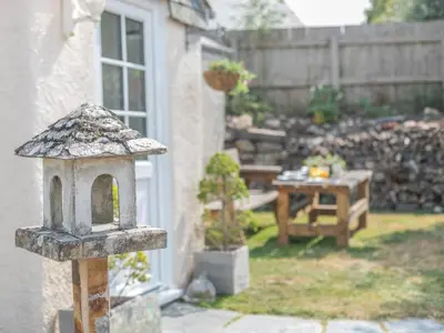 a garden with a table and a bird house at 1 Bed in Bude oc-tchawth in Saint Gennys