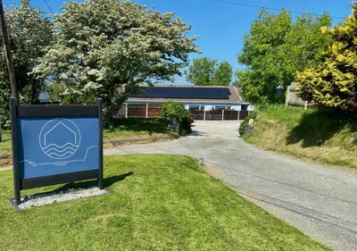 a sign in the grass in front of a house at 1 Bed in Bude oc-tchawth in Saint Gennys