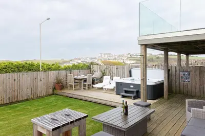 a backyard with a wooden deck with a table and a grill at Mermaid Gaze in Porth, Newquay in Newquay