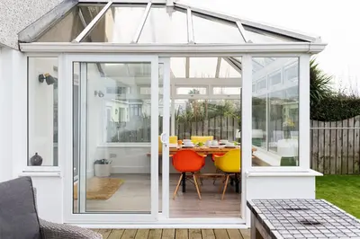 an extension of a conservatory with a table and chairs at Mermaid Gaze in Porth, Newquay in Newquay