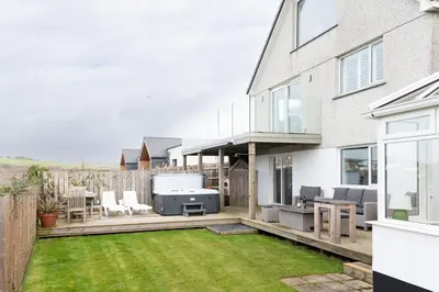 a backyard with a patio with a grill and grass at Mermaid Gaze in Porth, Newquay in Newquay