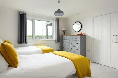 a bedroom with two beds with yellow blankets and a dresser at Mermaid Gaze in Porth, Newquay in Newquay