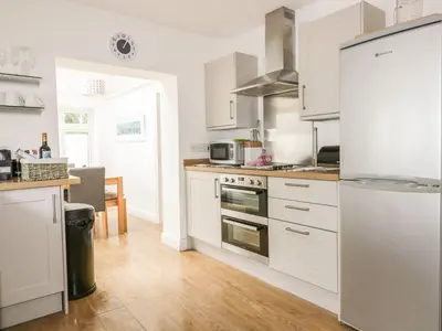 a kitchen with white cabinets and stainless steel appliances at Blacksmiths Cottage in Newquay