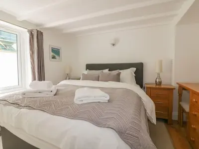 a white bedroom with a large bed with towels on it at Blacksmiths Cottage in Newquay