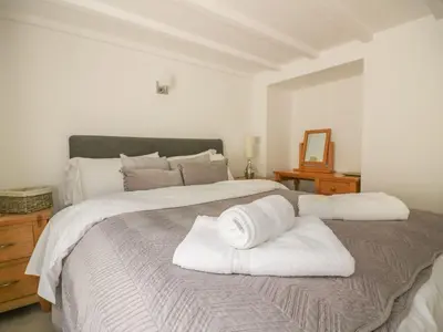 a large white bed with two white towels on it at Blacksmiths Cottage in Newquay