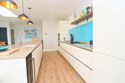 a kitchen with white cabinets and a wooden floor at Stylish townhouse in Padstow in Padstow