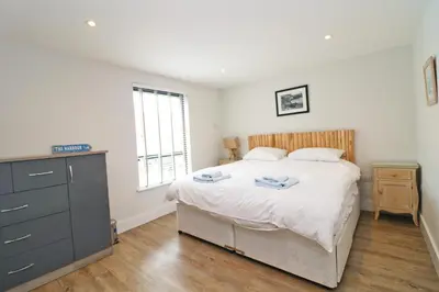 a bedroom with a bed with a dresser and a window at Stylish townhouse in Padstow in Padstow
