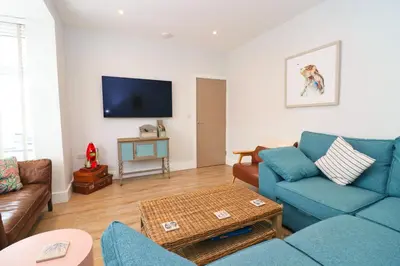 a living room with a blue couch and a tv at Stylish townhouse in Padstow in Padstow