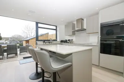 a kitchen with white counter chairs and a large window at Sailors in Falmouth