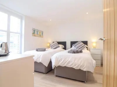 two beds in a bedroom with white walls at Sailors in Falmouth