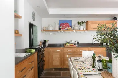 a kitchen with wooden cabinets and a counter with a table at La Folie, Fowey in Fowey