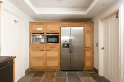 a kitchen with a stainless steel refrigerator and wooden cabinets at La Folie, Fowey in Fowey