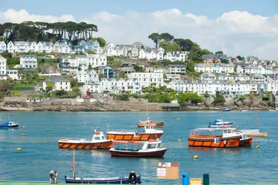 a group of boats in a body of water with houses at La Folie, Fowey in Fowey
