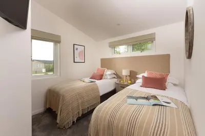 a bedroom with two beds and two windows at 5 Southern Place in Liskeard