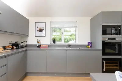 a white kitchen with a sink and a window at 5 Southern Place in Liskeard