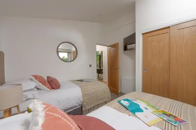 a bedroom with two beds and a mirror at 5 Southern Place in Liskeard