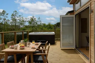 a wooden deck with a table and a hot tub at 5 Southern Place in Liskeard