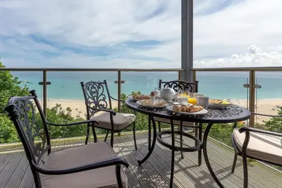 a table and chairs on a balcony with the beach at Abalone in St Ives