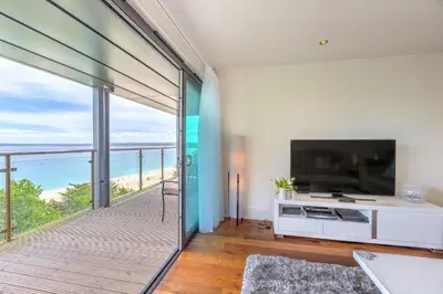 a living room with a large television and a balcony at Abalone in St Ives
