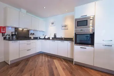 a large white kitchen with white cabinets and appliances at Abalone in St Ives