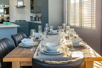 a dining room table with glasses and plates on it at Gull Rocks Beach Lodges in Cubert