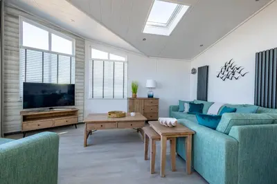 a living room with a blue couch and a tv at Gull Rocks Beach Lodges in Cubert