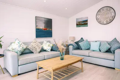a living room with a couch and a clock at Gull Rocks Beach Lodges in Cubert