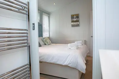 a small bedroom with a bed with white sheets at Gull Rocks Beach Lodges in Cubert
