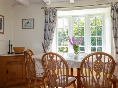 a dining room with a table and chairs and a window at Trewillig Cottage in Wadebridge