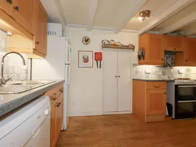 a kitchen with wooden cabinets and a white door at Trewillig Cottage in Wadebridge